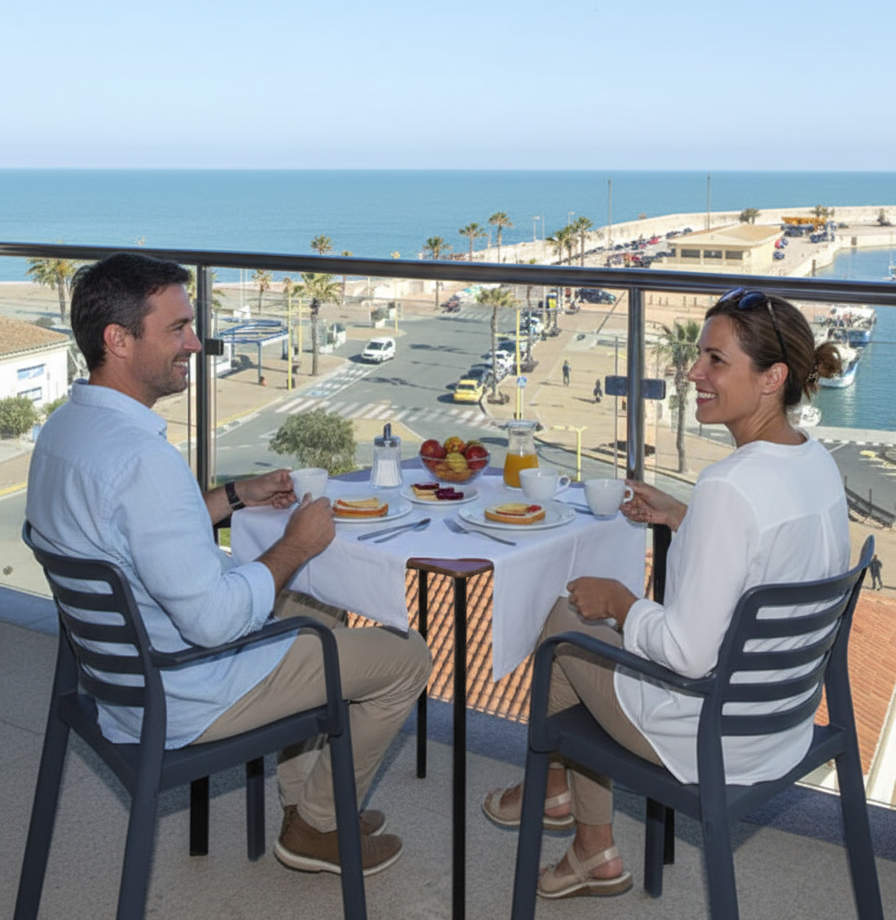 Pareja disfrutando de un desayuno en el balcón del apartamento con vista al mar de Ancla Spaces en Vinaròs.
